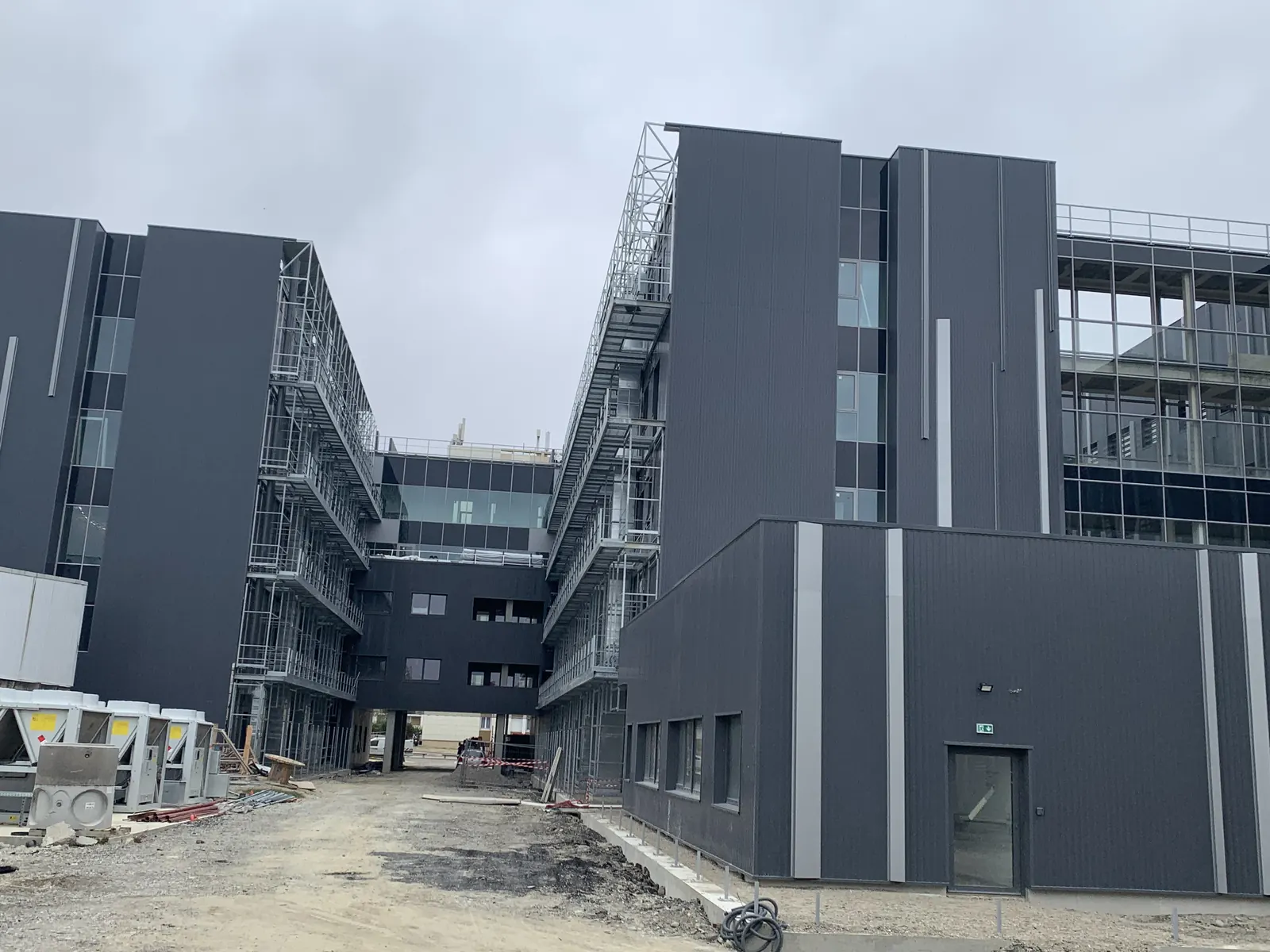 Bâtiments en R+4 du CMP reliés par des passerelles, échafaudages en façade